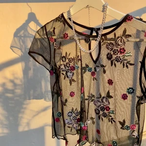 Festlig topp - 🖤 Säljer en svart genomskinlig festlig topp med broderade blommor 🌷🌸🌹 Den är super fin med linne eller tröja under, men man väljer själv hur man vill styla den 🌼 Den är i nyskick! Är du intresserad så kontakta mig, köparen står för frakt 🚚 📦 