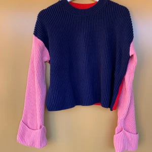 stickad tröja  - Stickad tröja från Carin Wester. Framsidan är blå och baksidan röd, armarna är breda. Tröjan är strl M. Frakten står köparen för.