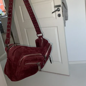 Väska  - En vinröd Noella väska med axelrem. 15x27 cm. Väldigt fint skick och har använt få gånger. Skriv om du är intresserad! Frakt ingår ej i priset. 