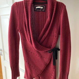Kofta från Bondelid - Vinröd kofta från Bondelid. Knytes omlott. Storlek L. Om den ska skickas på posten tillkommer fraktkostnad. Betalas med Swish. 