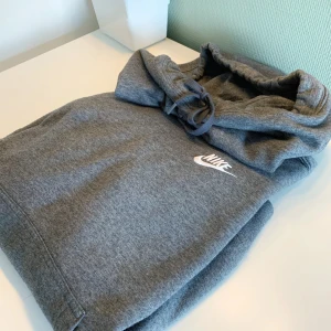 Nike hoodie - En grå Nike hoodie med "krage", använd någon enstaka gång. Aldrig tvättad så har kvar det mjuka på insidan😊 Frakt 66kr
