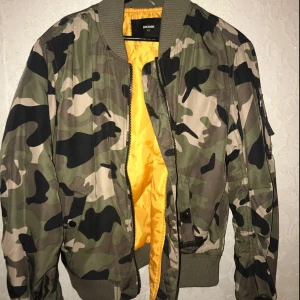  - Säljer en bomberjacka i militär, storlek X-Small. Aldrig använd. Från Bik Bok
