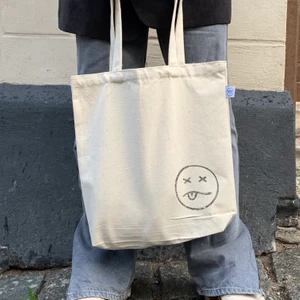Trendiga tygväskor - Coola tygväskor i 100% återvunnet bomull🤍 två färger/tryck. Går även att köpa plain väskor i båda färgerna för samma pris om man vill designa den personligt😊 OBS! Den ljusa väskan (se bild 1 och 2) har den glada smileyn på ena sidan och den andra smileyn på andra sidan, det är alltså samma väska:) ❌finns ett begränsat antal!!❌ Hitta mer info på vår Instagram @flaneur.uf 🖤