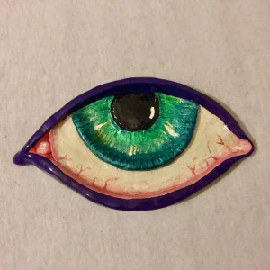 Asskopp - Askkopp/smyckesskål i form av ett öga, storlek ligger på ca 15cm i längd och 9cm i bredd. Koppen är hemmagjord och är lackad, så den är vatten och asktålig men tvättas helst med våt trasa!