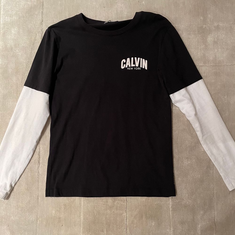En snygg långärmad t-shirt från Calvin Klein med svart t-shirt form och vita ärmar som sitter ihop. Knappt använd. . T-shirts.