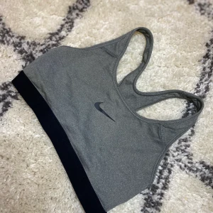 Sportbh Nike stl S - Grå Nike sporttopp stl S, utan bygel och vaddering. Mycket fint skick samt doftfri då den i stort sett är oanvänd. Varken hål eller repor på Nike märket.
