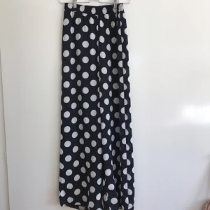  - Vida byxor med resår i midjan. Mörkblå botten med vita prickar.