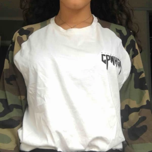  - Vit långärmad tröja med camouflageärmar. Står i storleken M men funkar även om man har storlek S, då den blir lite oversized. Köparen står för frakt, Annars kan jag mötas upp i Stockholm