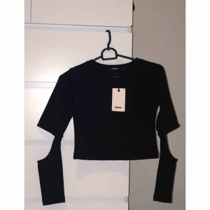  - Svart tight topp från Bik Bok. Snygg design med öppna armbågar. Passar perfekt till ett par högmidjade byxor. 
