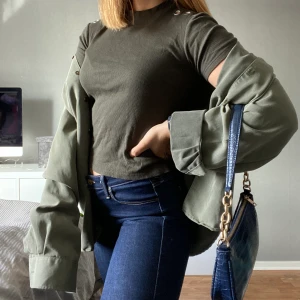 Grön tröja - Mörkgrön tröja med cool detalj på axlarna. Använd men fint skick. Storlek S, 40kr + frakt.