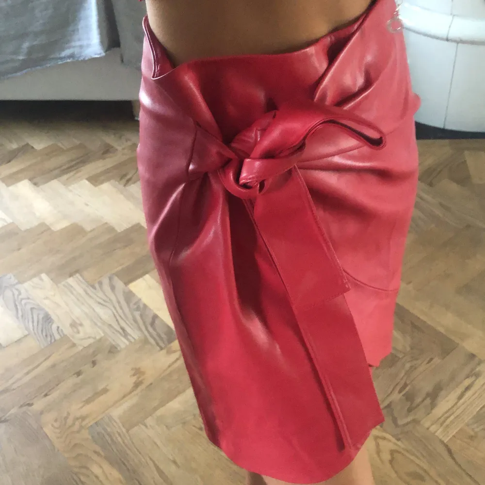 En röd lack kjol från Mango draperad med en rosett och dragkedja bak. Kjolar.