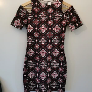 Mönstrad klänning  - Jättefin kort och mönstrad klänning från H&M. Kortärmad med cut outs på axlarna. Den är figursydd och tight, sitter perfekt på kroppen.  Storlek 36 passar även 34. Använd ett fåtal gånger, i nyskick.