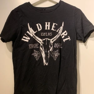 Svart T-shirt - gina - xs - Svart tröja med tryck framtill, från gina tricot i storlek xs (passar s med). 35kr + frakt. OBS FLÄCK, se bild (Vet ej vad det är och har inte testat att få bort det) därav priset. 