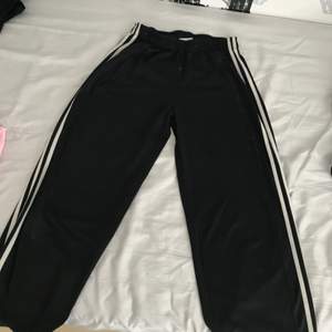 Ett par svarta Adidas byxor i storlek S som dessutom passar för de med storlek M.  