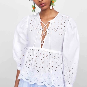  - Ombloggad och slutsåld broderad topp från Zara med V-ringning och snörning, puffärmar med breda ärmslut, och nederkanten har breda volanger med vågor.   Ny med lapp kvar.  Nypris: 349kr