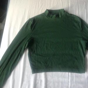  - Supersnygg mörkgrön långärmad croptop! Endast använd en gång så den är som ny. Jätteskönt, mjukt, ribbat material.  Köparen står för eventuell frakt! 
