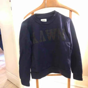  - Mörkblå collagetröja från Wood Wood. Supersnygg! Använd fåtal gånger och i fint skick.  Kan skickas mot fraktkostnad eller mötas upp i sthlm.