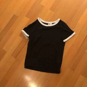  - En svart t-shirts med vit runt armarna