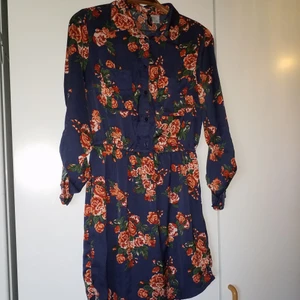 Klänning med rosor - Jättefin och mycket lite använd klänning i sidenlikt material. Resår i midjan och ärmar som knäpps upp