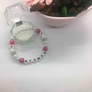 Armband ”MORMOR” kärlek    Fin armband i vit och rosa pärlor.  Handgjorda med elastiktråd och passar till alla handleder. Storlek : 17-18 cm