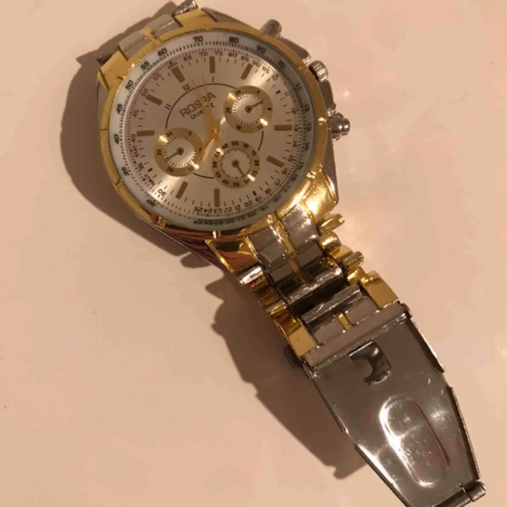 En jätte fin klocka i märket ROSRA. Den är guld och silver. Inga repor eller sådant, i fint skick och batteriet funkar. Passar både dam och herr. . Accessoarer.