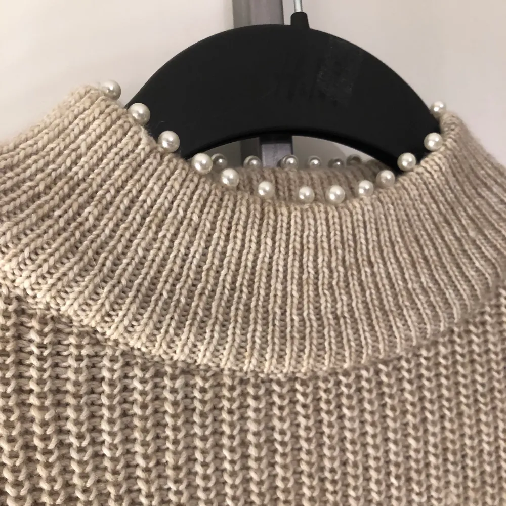 En beige stickad tröja från H&M med pärlor på kragen, storlek S. Använd endast en gång och har inga fel. . Stickat.