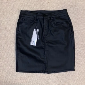 Noisy May läderimitation kjol i strl S - Kjolen är en minikjol i läderimitation som formar sig snyggt på kroppen. Köpte den för två år sedan för 300kr på Vero Moda. Den är aldrig använd bara testad (prislapp kvar), säljer då det inte är min stil och hoppas någon annan kan få användning av den, då den bara tar plats i garderoben. (Fråga gärna om ni undrar något)