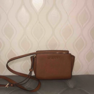  - En liten brun väska med axelband. Nypris 2000kr säljs 850kr nyskick! (ÄKTA) köpt i original butik!   Vid intresse fler bilder finns!   Köparen står för frakt!