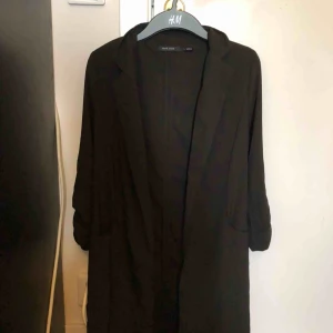  - Svart trenchcoat Har uppkavlade armar som man kan justera  