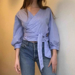  - Wrap-skjorta. Perfekt krispigt men mjukt sommartyg. KLASSIKER. Kan knytas hur man vill fram/bak bild1/2. 