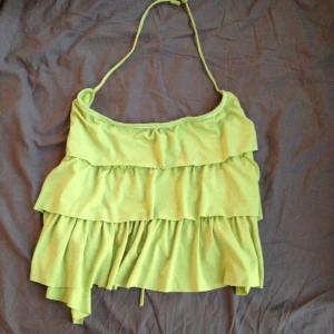  - Somrigt halterneck-linne med snörning i hals och rygg. Fina volanger och diskret paljett-detalj i ringningen. Justerbar storlek S-L. Oanvänd. 
FRI FRAKT!