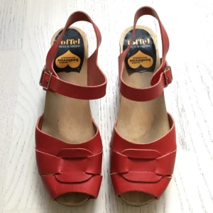  - Röda Hasbeens, Pep Toe High stl. 39, i bra använt skick.   Finns ett hack i sulan vid ena tån  (bild 3)men syns knappt på samt att träklackarna har lite märken men går enkelt att slipa bort om man vill.