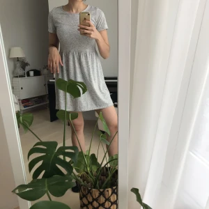  - Grå, kortärmad klänning med mörkare prickar. Superskönt material och luftig sommarklänning. Knappt använd. Frakt ingår i priset.  