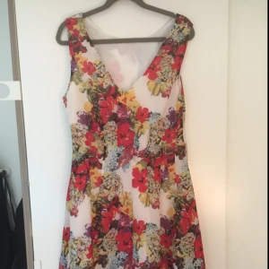  - Fin blommig klänning, perfekt till midsommar, går att använda med den v-ringade sidan framtill eller i ryggen.
