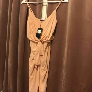  - Jättefin klänning som är helt oanvänd med prislappen kvar! puderrosa i färgen och materialet är stretchigt och lite glansigt. Sitter perfekt då klänningen har knytning i midjan, och sedan faller snyggt längs med kroppen🙌🏻✨