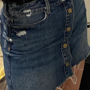 Jeanskjol i storlek S från Zara - Jeanskjol med knappar och slitningar på. I bra skick