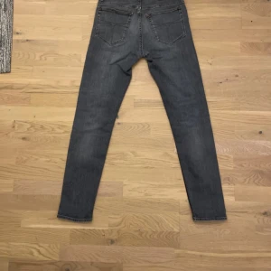 Grå Tiger of Sweden jeans Evolve 31/32 - Säljer ett par grå jeans från Tiger of Sweden i modellen Evolve. Jeansen har klassisk femficksdesign, raka ben och normal passform. Tillverkade i Italien av slitstarkt bomullsmaterial. Perfekta för dig som gillar stilrena och tidlösa jeans. Pris kan diskuteras.