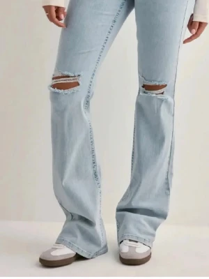 Ljusblå bootcut jeans med hål - Säljer dessa ljusblå jeans från Nelly med detaljer i rosa på bakfickorna. Säljer då dom är för tighta så kommer inte till användning💞