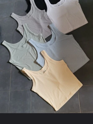 Ribbad croppad topp i pastellfärger - Säljer flera ribbade croppade linnen i olika pastellfärger som ljusgul, ljusblå, ljusgrön samt Basic färger som grå svart och vit. Alla har breda axelband och rund halsringning, perfekta för att bära som en undertröja under skjortan kalla dagar på kontoret eller varför inte använda till våren och sommaren elr utlandssemestern. Kom gärna med eget prisförslag