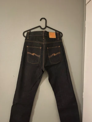 Nudie Jeans Average Joe 30/32 - Mörkblå jeans från Nudie Jeans modell Average Joe i storlek 30/32. Klassisk rak passform med orange kontrastsömmar. Inte alls använda. Perfekt för dig som vill sticka ut lite då de är från 2008! Pris ej hugget i sten. 