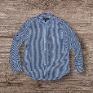 Blårandig skjorta från Ralph Lauren - Klassisk blårandig skjorta från Ralph Lauren med vit botten och smala blå ränder. Skjortan har lång ärm, knappar framtill och ikoniska broderade loggan på bröstet. Tillverkad i mjuk bomull och har en tidlös krage. Sitter som S