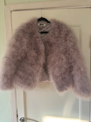 Grå pälsjacka från DM - Super fin fluffig jacka i grå nyans. Kort modell med mjukt foder inuti. Använd fåtal gånger och mycket fint skick. Perfekt till fest eller som Statement-jacka. Har en fläck på insidan men inget som syns när man har på sig den. 