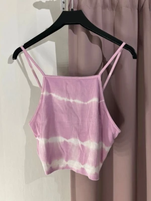 Lila ribbad linnetopp från Zara - Säljer en lila ribbad linnetopp från Zara med tunna axelband och vit batikmönstring. Toppen är croppad och har en mjuk, stretchig känsla som passar perfekt till sommaren. Supersnygg att styla med jeans eller kjol för en chill look.