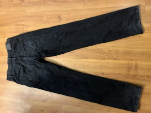 Svarta jeans från Nudie Jeans Co - Säljer ett par svarta jeans från Nudie Jeans Co. Klassisk femficksmodell med raka ben och normal passform. Jeansen har silverfärgade knappar och subtil Nudie Jeans Co-detalj vid fickan. Perfekta till en avslappnad stil.