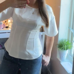 Vit topp - Säljer en vit figursydd topp💞 Toppen har rund halsringning, korta ärmar och en synlig dragkedja i ryggen. Perfekt till jeans eller kjol. Endast använd en gång!