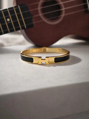 H-armband  - Säljer ikoniska H-armband i guldpläterad metall med emaljdetaljer. Finns i svart, vit, röd, rosa, gråblå och orange. Snyggt H-spänne framtill och stilren design som lyfter din outfit. Perfekt accessoar för dig som gillar lyx och färg