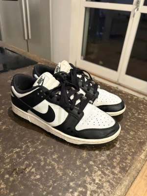 Nike Dunk Low Panda - Nike Dunk Low “Panda” i storlek 40. Använda men i bra skick, inga hål eller sprickor. Sulan har bra grepp kvar och skorna är fortfarande fräscha att använda. Klassisk färg som passar till allt. Skickas snabbt efter köp. Kan sänka pris vid snabb affär. 