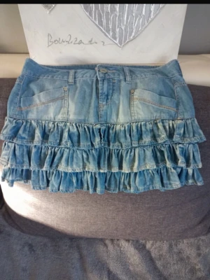 Blå jeanskjol med volanger - Supersöt kort jeanskjol med volanger. Super fin och trendig. Storlek 36 och midjemåttet rakt över är ca 38cm❤️ 