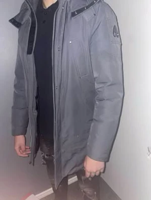 Moose Knuckles cloud 9 jacka M - Säljer en grå dunjacka från Moose Knuckles med huva och svarta detaljer. Jackan har flera fickor, dragkedja framtill och logga på ärmen. Insidan är svart och quiltad för extra värme. Perfekt för kalla dagar, pris kan diskuteras, Jackan är köpt 2023 vinter. Knappt använd.