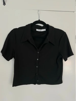 Svart ribbad kortärmad topp från NA-KD, storlek S - Kortärmad svart croppad ribbad topp från NA-KD i storlek S. Knappt använd en handfull gånger. - Köper du innan kl 16:00 kan jag posta samma dag!